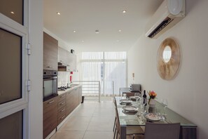 Eine moderne Küche mit Essbereich, ausgestattet mit einem Glastisch, der für das Essen gedeckt ist, einem großen Spiegel an der Wand und einer Klimaanlage.