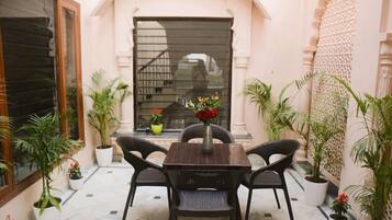Un patio con una mesa y sillas, rodeado de plantas en macetas.