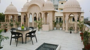 A terrace with a table and chairs, surrounded by potted plants and architectural domes. - Gupta Vilas - A Boutique Homestay - Standard King Room 2 (Agra)