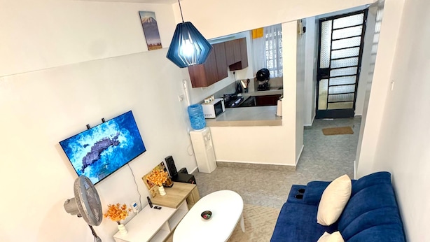 A modern living room with a blue sofa set, a white coffee table, and a flat-screen TV mounted on the wall. - Modern two bedroom apartment in Central Kisumu. Wifi and secure parking (Kisumu)