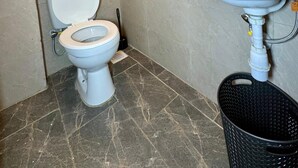 A bathroom with a toilet, sink, and a small window with cleaning supplies. - Modern two bedroom apartment in Central Kisumu. Wifi and secure parking (Kisumu)