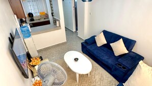A modern living room with a blue sofa, a small white table, and a ceiling fan. - Modern two bedroom apartment in Central Kisumu. Wifi and secure parking (Kisumu)