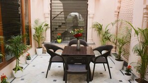 A patio with a table and chairs, surrounded by potted plants. - Gupta Vilas - A Boutique Homestay - Standard King Room 4 (Agra)