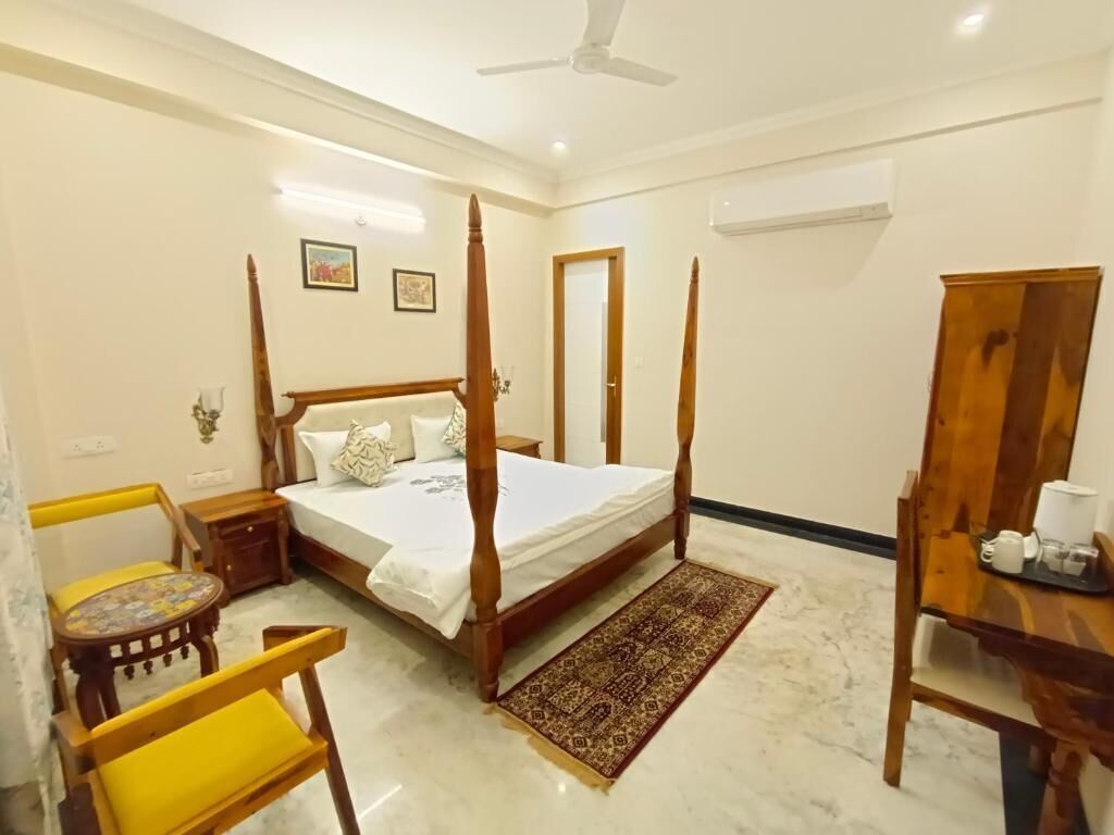 A bedroom with a four-poster bed, a wooden chair, a small table with a tray, and a patterned rug.