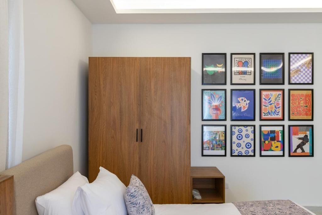 Un dormitorio con cama, armario y una pared decorada con obras enmarcadas.