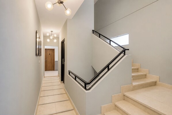 A modern staircase with a glass railing, leading to a landing with a wooden door.