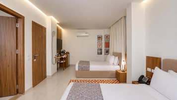 Una habitación de hotel con cama, mesita de noche, lámpara y un escritorio con silla.