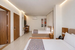 Una habitación de hotel con cama, mesita de noche, lámpara y un escritorio con silla.