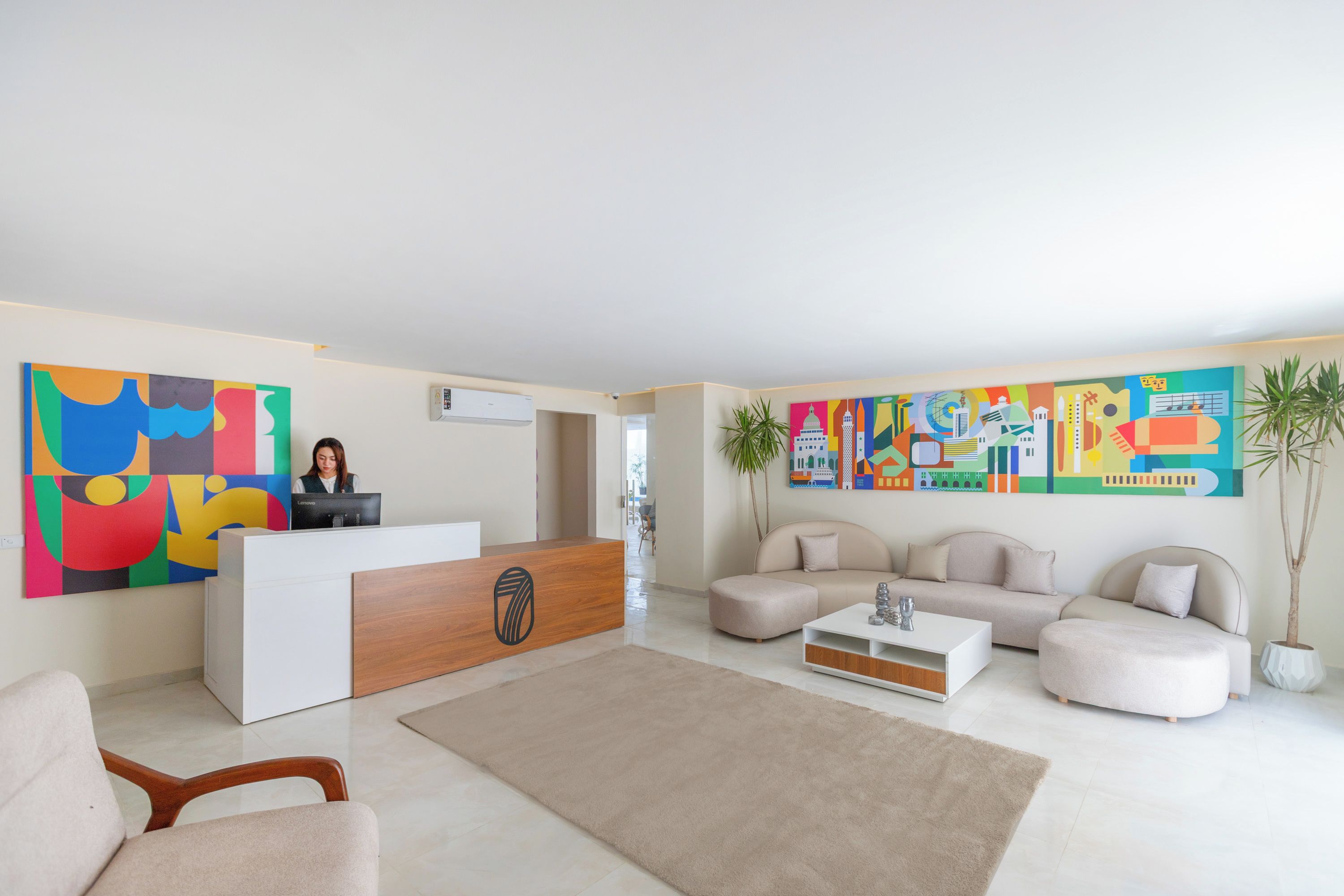 Una moderna zona de recepción con un escritorio de madera, una recepcionista y un cuadro abstracto y colorido en la pared.