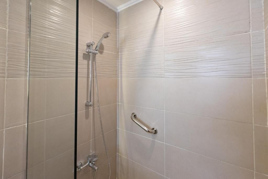 A shower with a glass door, a handheld showerhead, and a wall-mounted faucet.