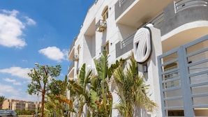 A modern building with balconies, a garage door, and tropical plants. - Seven Stays Centric West  (Giza Governorate)