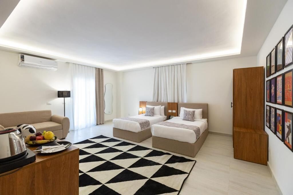 Una habitación de hotel moderna con dos camas, un sofá, una mesa de centro y una alfombra con estampado en blanco y negro.