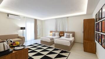 Una habitación de hotel moderna con dos camas, un sofá, una mesa de centro y una alfombra con estampado en blanco y negro.