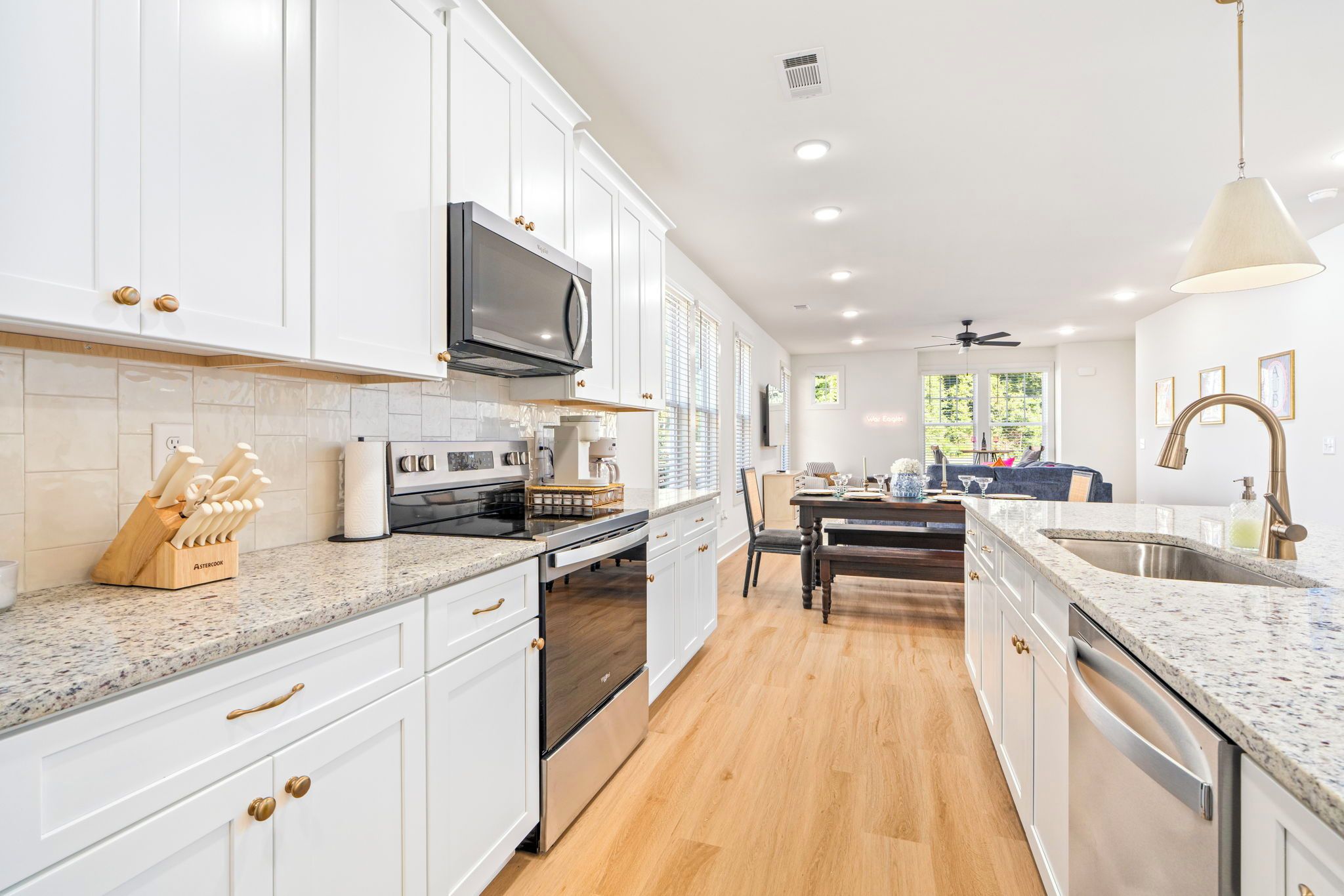 A modern kitchen with white cabinetry, stainless steel appliances, and a granite countertop.