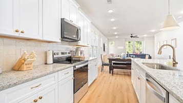 A modern kitchen with white cabinetry, stainless steel appliances, and a granite countertop.