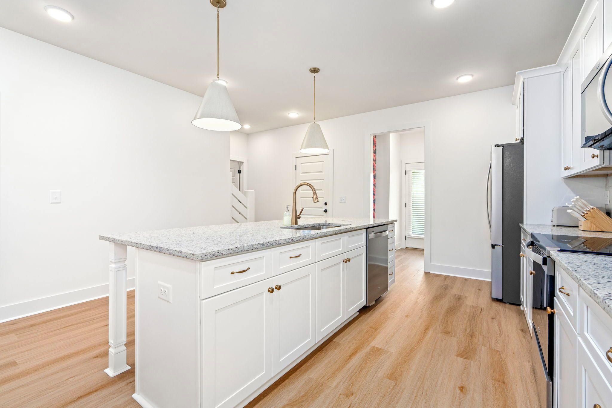 A modern kitchen with white cabinetry, granite countertops, and stainless steel appliances.