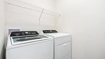 Ein kompakter, moderner Waschraum mit einer Waschmaschine und einem Trockner mit Frontlader, einem Metalldöriggerüst und einem kleinen weißen Schrank.