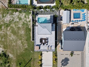 Luchtbeeld van een woonhuis met zwembad, terrasmeubilair en een overdekt buitengebied.