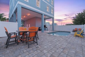A poolside area with a covered seating area, a pool, and a view of a residential building in the background. - 🌴Salty Seahorse Unit 200 | Heated Pool | Steps to Beach🌞 (Fort Myers Beach)