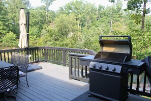 A deck with a grill, chairs, and an umbrella. - Luxurious Lakefront House on Private Lake Lorraine near all Innsbrook Amenities! (Innsbrook)