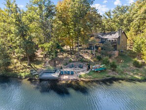 Propiedad junto al lago con muelle, asientos al aire libre y una casa.