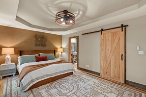 A bedroom with a large bed, two bedside lamps, a wooden wardrobe, and a ceiling light fixture.