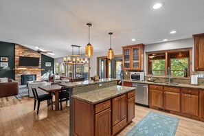 A modern kitchen with wooden cabinets, granite countertops, and pendant lighting.