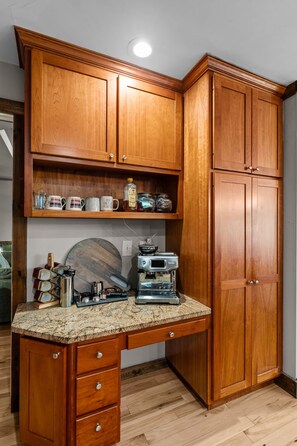 A kitchen with wooden cabinets, a granite countertop, and a coffee machine.