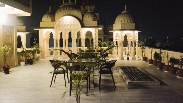 Un patio con un edificio de arquitectura abovedada y una zona de estar con sillas y plantas en macetas.