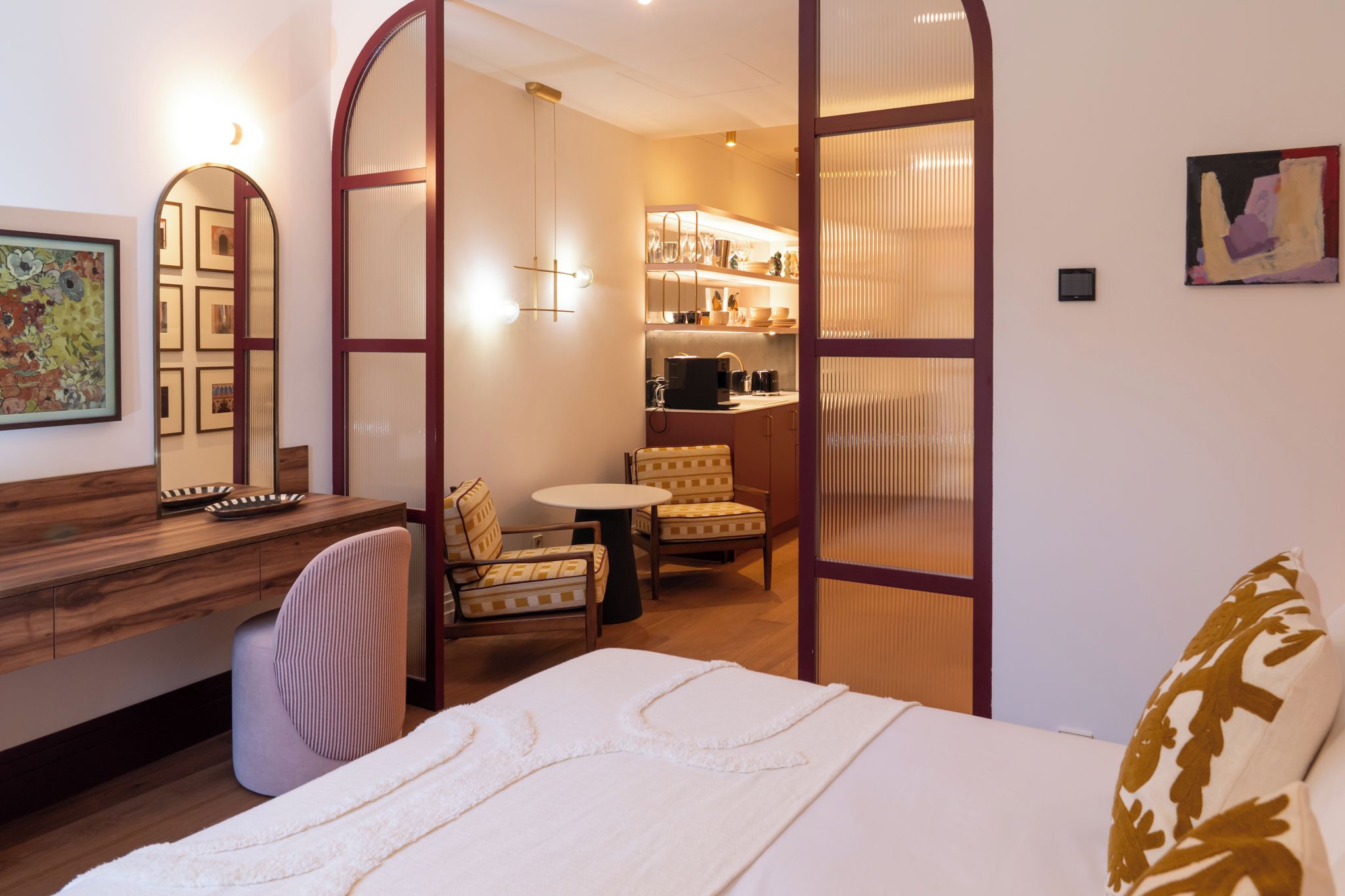Una habitación de hotel con una cama, un escritorio, una silla, una mesita y una kitchenette.