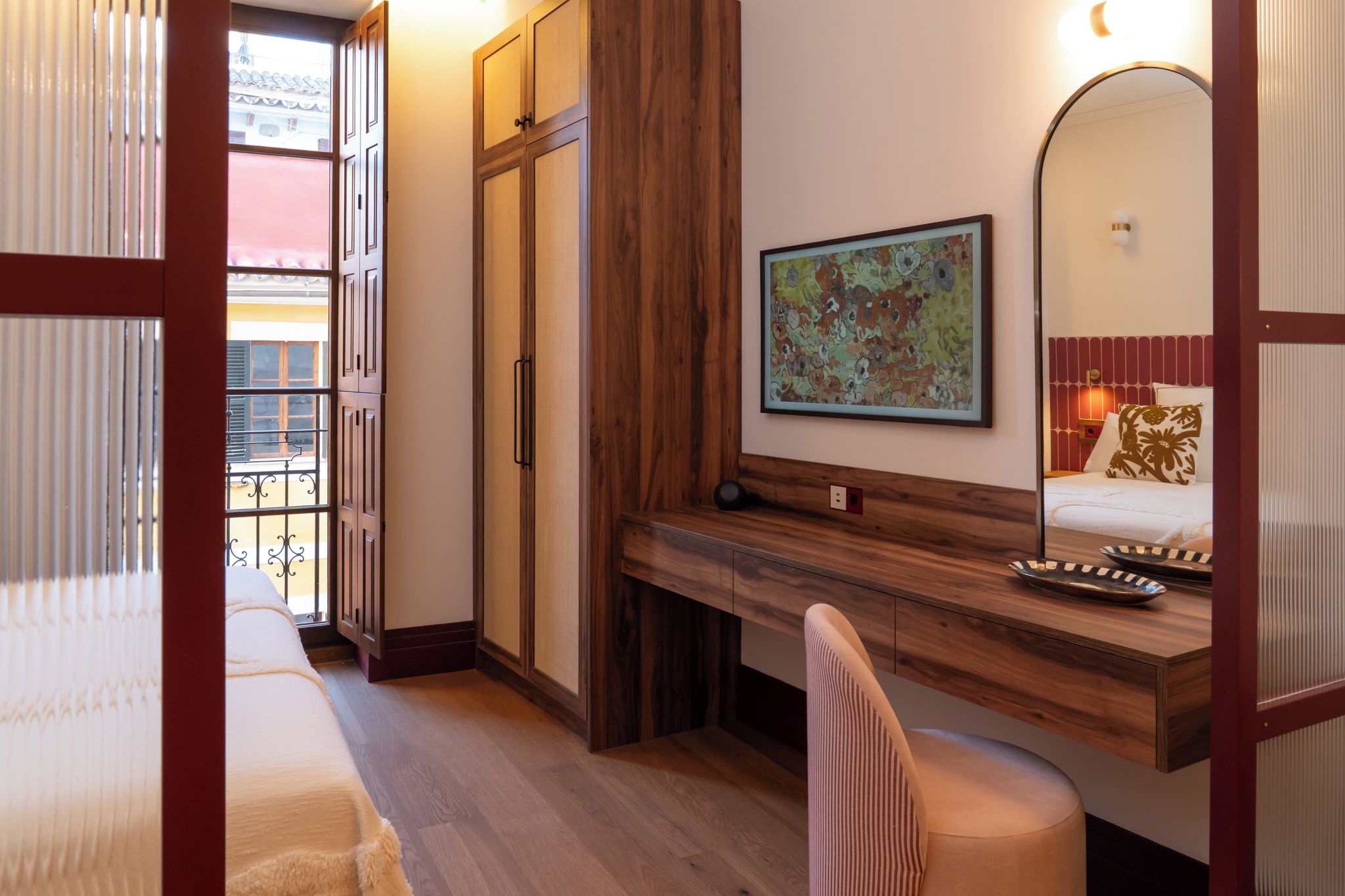Una habitación de hotel con una cama, un escritorio, una silla, un espejo y un cuadro en la pared.