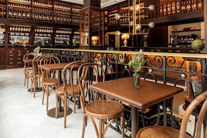 A bar area with wooden tables and chairs, a wine rack, and a globe on the wall.