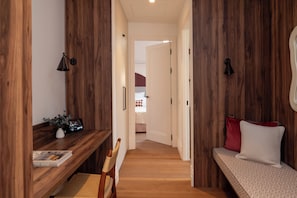 A hallway with wooden paneling, a desk with a book, a chair, and a bench with pillows. - Casa Roca (Palma de Mallorca)