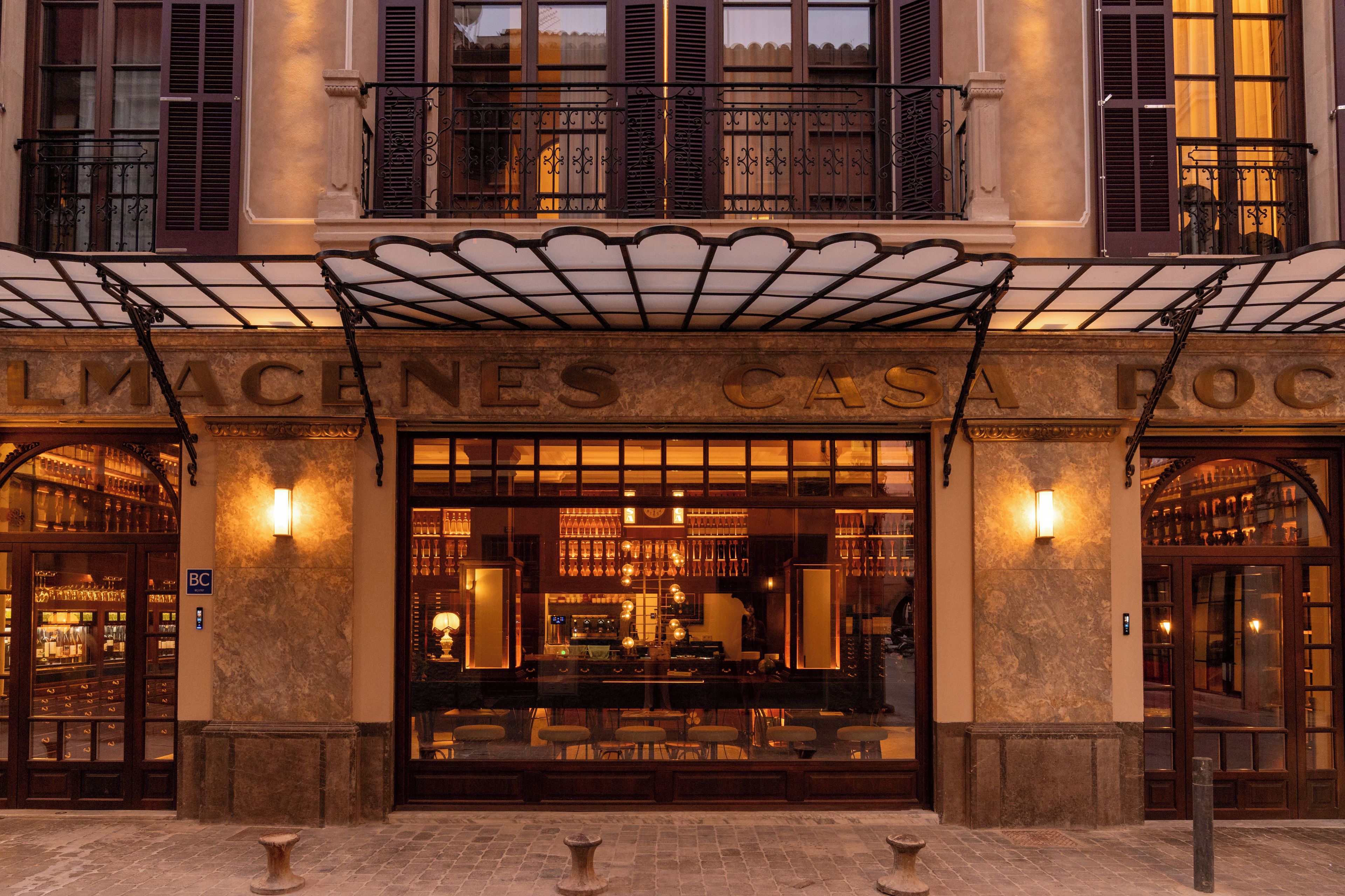 La entrada de un hotel con un acceso cubierto, amplios ventanales de vidrio y un letrero sobre las puertas.