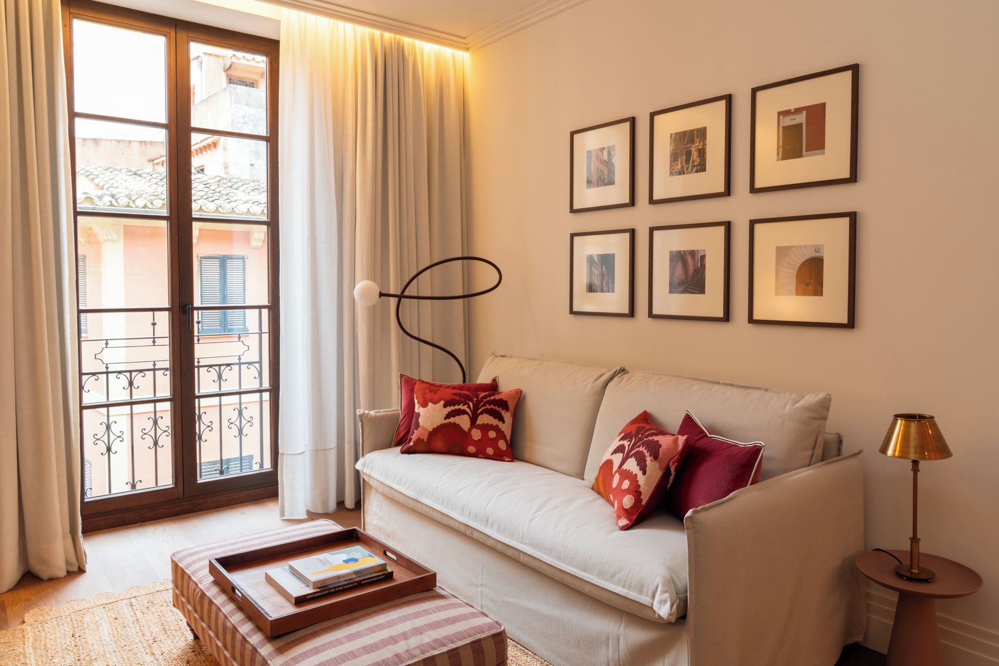 Una sala de estar con un sofá, una mesa de centro, una lámpara de pie y una ventana con cortinas.