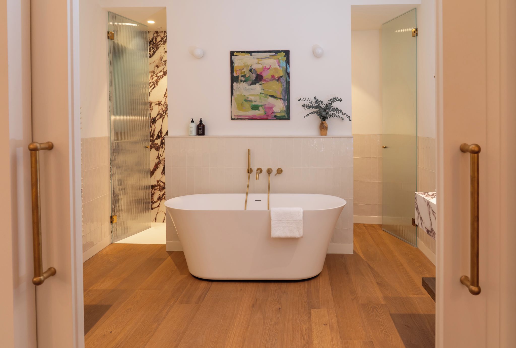Un baño moderno con una bañera independiente, cabina de ducha de vidrio y pared de mármol.