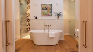 Un baño moderno con una bañera independiente, cabina de ducha de vidrio y pared de mármol.