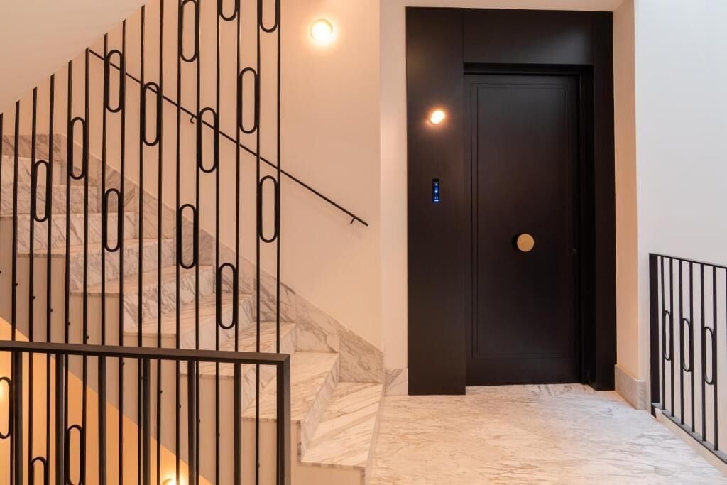 Una escalera de diseño moderno, una puerta oscura y una lámpara.