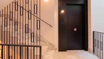 Una escalera de diseño moderno, una puerta oscura y una lámpara.