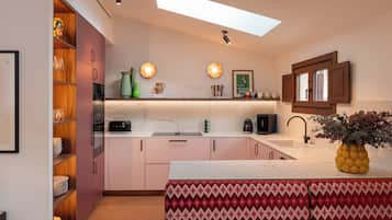 Una cocina moderna con una isla central, electrodomésticos integrados y un tragaluz.