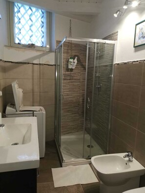 Een badkamer met een douche met glazen wand, een wastafel en een toilet.