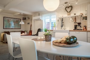 A modern kitchen with white cabinetry, a dining table with chairs, and a large window with a view.