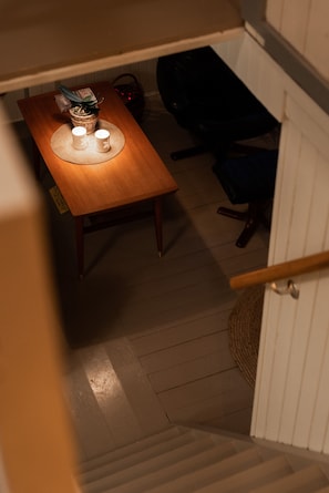 A wooden dining table with a placemat, two white candles, and a potted plant.