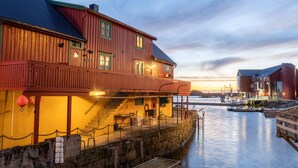 A waterfront building with a wooden facade, a balcony, and a dock extending into the water. - Cozy seaside cabin in Stamsund (Stamsund)