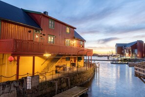 A waterfront building with a wooden facade, a balcony, and a dock extending into the water. - Cozy seaside cabin in Stamsund (Stamsund)