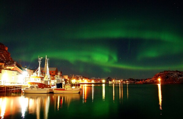 A harbor at night with boats docked, buildings, and the aurora borealis. - Cozy seaside cabin in Stamsund (Stamsund)