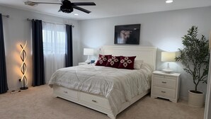 A bedroom with a bed, bedside tables, a ceiling fan, a wall-mounted TV, and a potted plant. - Hilltop house with city view w/pool & jacuzzi (San Antonio)