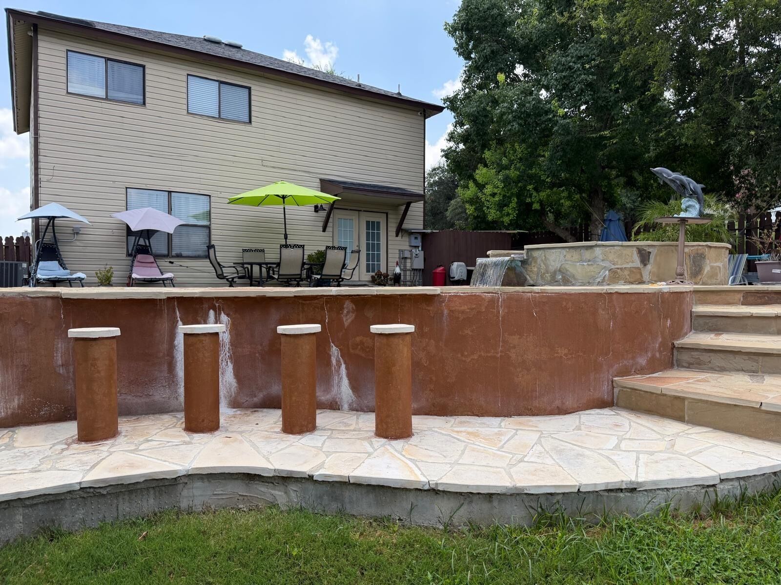 A patio area with outdoor furniture, a stone wall, and a water feature.