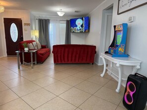 Una sala de estar con un sofá rojo, televisión y una máquina de videojuegos Pac-Man.