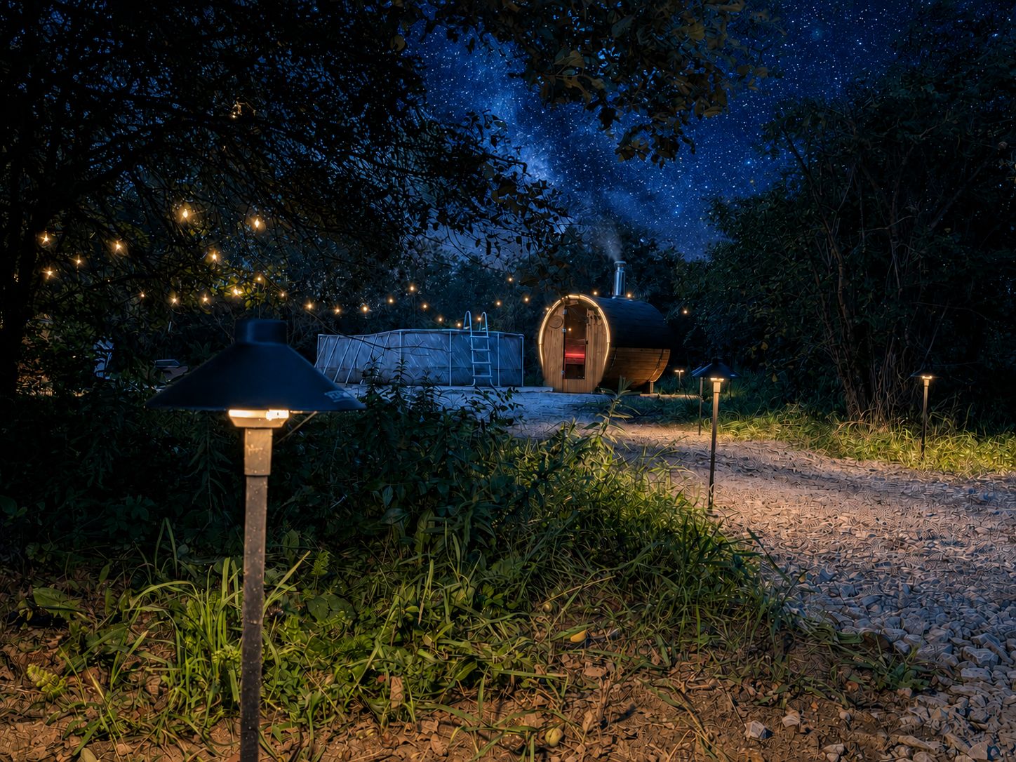 A rustic outdoor setting with a wooden structure, a metal barrel-shaped building, and a pathway leading to a lit area.